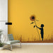 Une chambre lumineuse avec un papier peint illustrant un enfant tenant un grand tournesol sur fond jaune, créant une atmosphère joyeuse et inspirante.
