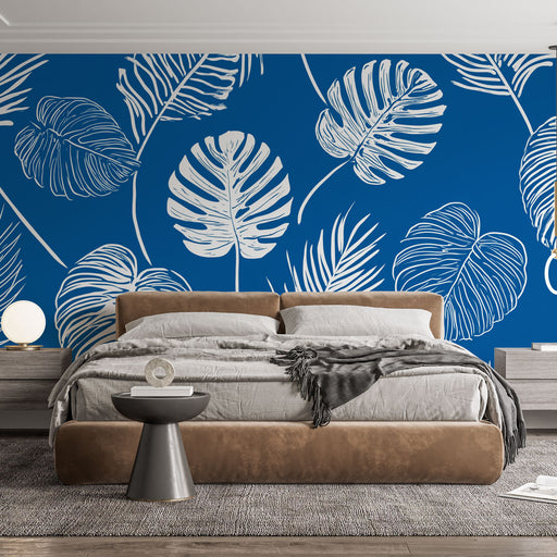 Une chambre moderne avec un papier peint tropical bleu vif orné de grandes feuilles blanches, créant une atmosphère dynamique et apaisante.