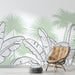 Une salle de séjour moderne avec un papier peint tropical aux motifs de feuilles de bananier et de palmiers sur fond vert doux, créant une ambiance fraîche et apaisante.