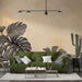 Un salon moderne avec un papier peint représentant de grandes feuilles tropicales noires sur un fond beige, créant une atmosphère chaleureuse et accueillante.