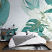 Une chambre moderne avec un papier peint tropical aux grandes feuilles vertes et des fleurs délicates sur fond clair, créant une atmosphère apaisante et naturelle.