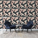 Un salon moderne avec un papier peint tropical aux motifs de palmiers noirs et roses sur fond crème, créant une ambiance chaleureuse et accueillante.