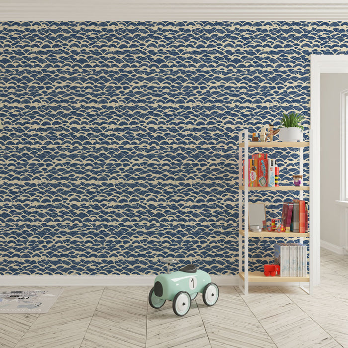 Une chambre d'enfant avec un papier peint bleu marine orné de motifs de vagues blanches, créant une ambiance ludique et apaisante.