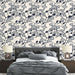 Une chambre élégante avec un papier peint floral bleu marine sur fond clair, évoquant une ambiance apaisante et raffinée.