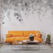 Un salon moderne avec un papier peint aquarelle représentant des feuilles grises délicates sur fond blanc, créant une atmosphère apaisante et élégante.