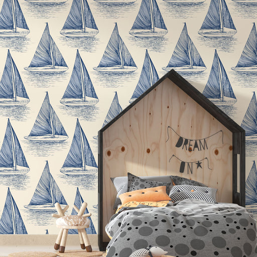 Une chambre enfantine avec un papier peint nautique représentant des voiliers bleus sur fond crème, créant une ambiance sereine et rêveuse.